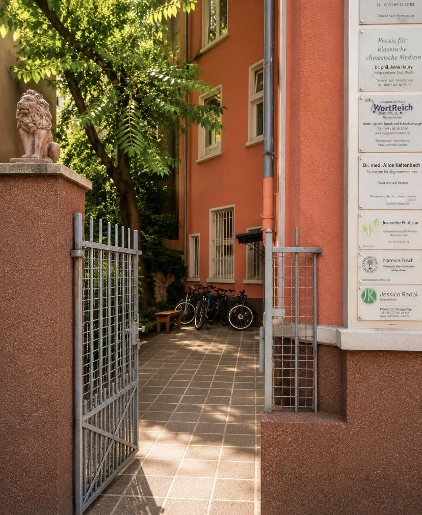 Eingang durch den ruhigen Innenhof mit Praxisschild